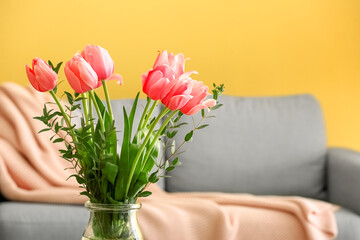 Glass vase with pink tulips in living room, closeup