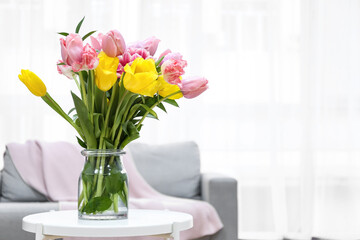 Fototapeta na wymiar Glass vase with spring flowers on table in living room