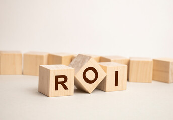 ROI word written on wood block. ROI - Return on Investment - word is made of wooden building blocks lying on the yellow table. ROI, business concept, yellow background