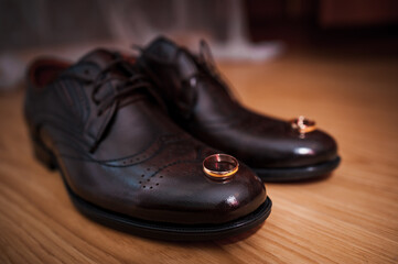 Leather men's shoes, a pair of gold wedding rings in a wooden box. Groom's accessories