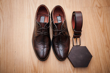 Leather men's shoes, a pair of gold wedding rings in a wooden box. Groom's accessories