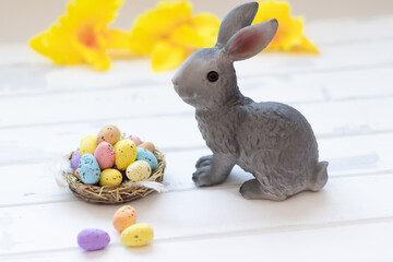 happy easter day, easter bunny and eggs in a nest on a white wooden background