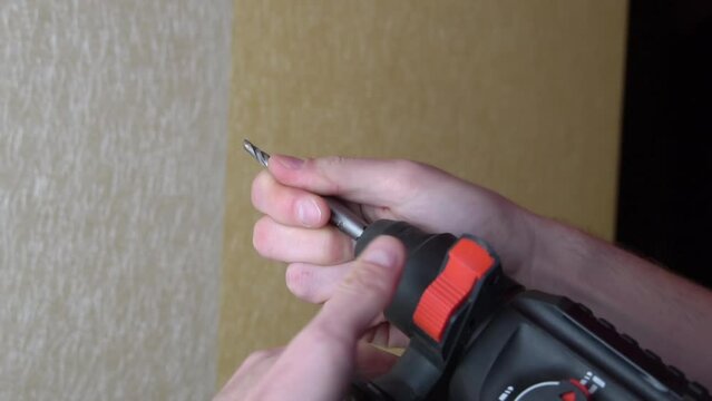 Male hands drill a hole in the wall with a wallpaper drill. Repair in the apartment. the master drills a hole in the wall with a drill. DIY home improvement.