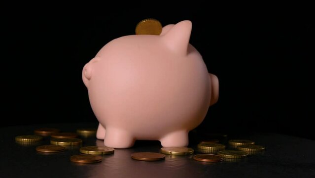 pink piggy bank with euro cents rotates on a black background 