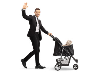 Full length profile shot of a smiling man in a suit and tie pushing a dog stroller and waving