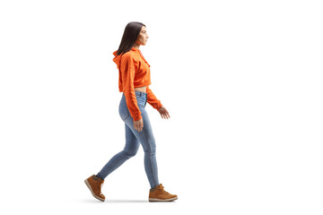 Full length profile shot of a young female in jeans and sweatshirt walking