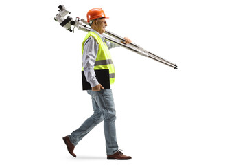 Full length profile shot of an engineer walking and carrying measuring instrument
