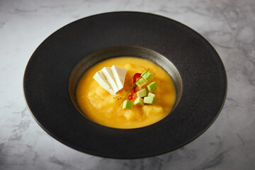 Ecuadorian locro de papa a traditional potato and cheese soup served with avocado and hominy. It’s on a wooden background