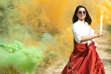 Multicolored smoke bombs cloud of dry color Holi powder colour gulal abeer and Beautiful young girl woman dance enjoy event in spring break in the park Holi festival of color