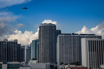 Fototapeta na wymiar A block of tall office and condo buildings in downtown Miami, Florida with an airplane flying above them during bright, sunny day