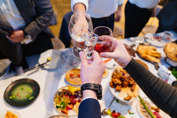 hands with glasses above the festive table