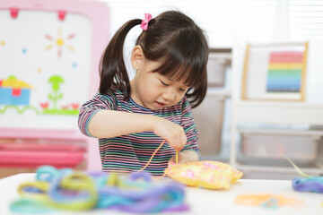 young girl sewing pad craft using plastic needle and yarn for home schooling