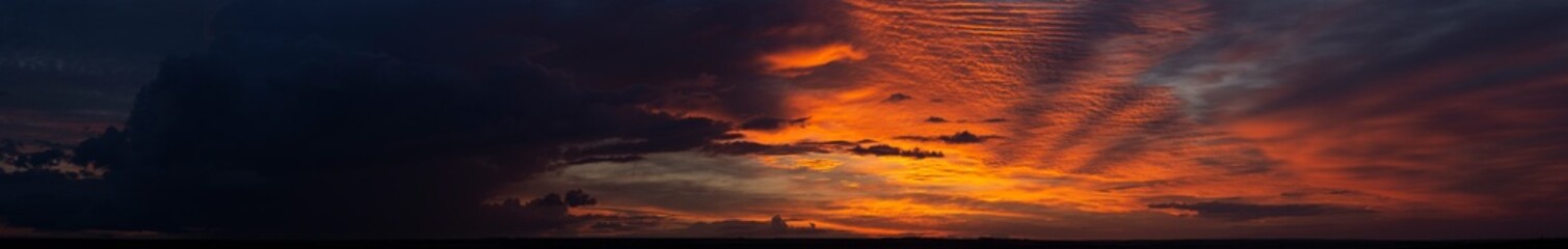 Landscape with bloody sunset. Panorama. Tragic gloomy sky. The last flashes of the sun on the storm...