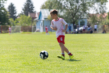 The little football player practicing his football skill alone at the playground.