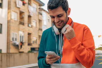 man with mobile phone and earphones in the street with successful expression