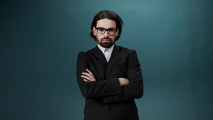 Fototapeta premium A handsome young man with long hair in a black suit and shirt taking on the eyeglasses