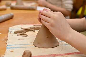 A girl sculpts a doll out of clay.