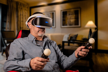 Hombre mayor disfrutando de sus juegos en realidad virtual en el living room de su casa