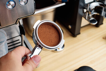 Closeup of  barista holding coffee ground on portafilter coffee basket       