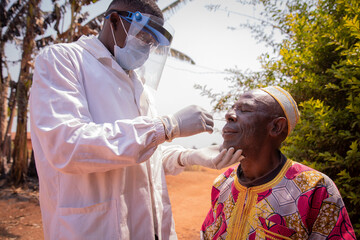 A doctor performs a coronavirus test with a swab on an elderly African patient. Covid-19 test in...