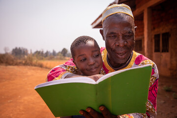 African grandfather reads a book with his grandson, moment of love and tenderness between them....