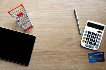 Top table of tablet mockup and credit card and calculator on wooden surface. Concept for money...