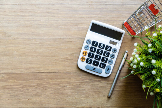 Close up shopping cart and calculator on wooden surface. Concept for money spending and financial background