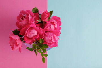 Top view of roses in bouquet on pink and blue background with copy space for mothers day holiday.
