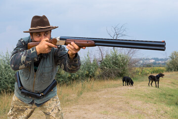 Hunter man in camouflage with a gun during the hunt in search of wild birds or game. Autumn hunting season.