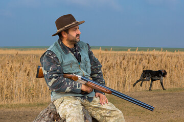 Hunter man in camouflage with a gun during the hunt in search of wild birds or game. Autumn hunting...
