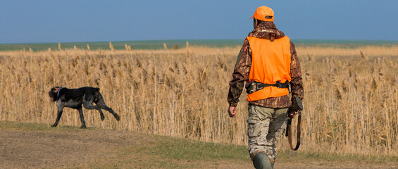 Hunter man in camouflage with a gun during the hunt in search of wild birds or game. Autumn hunting...