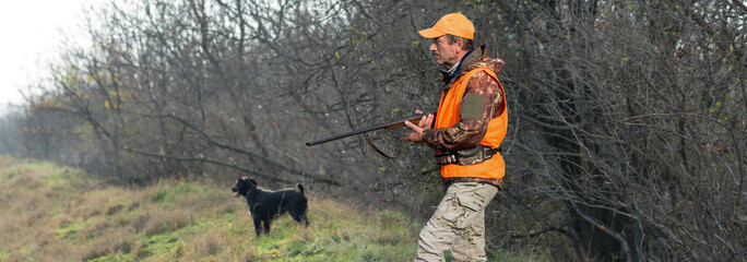 Hunter man in camouflage with a gun during the hunt in search of wild birds or game. Autumn hunting...