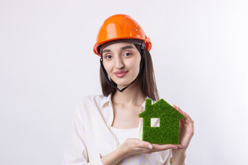 A young girl architect in a construction helmet demonstrates a model of a green house. Sale of ecological real estate.