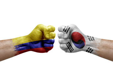 Two hands punch to each others on white background. Country flags painted fists, conflict crisis concept between colombia and south korea