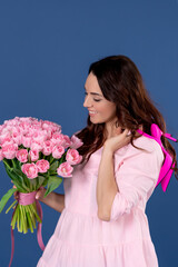 Portrait of cute attractive cute cheerful dreamy woman with pink shoes holding tulips on blue color background
