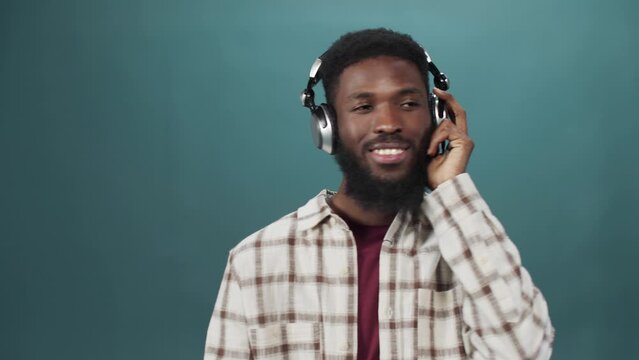 An african young man in a white shirt is listening to music and dancing