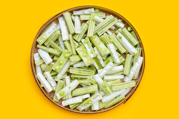 Moringa oleifera cut in pieces in bamboo weave plate on yellow background.