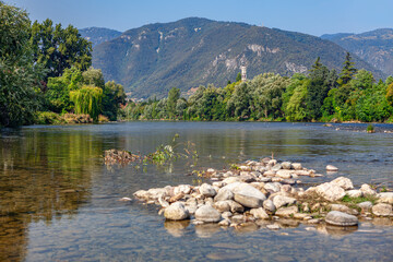 Brenta river and Alps in Bassano del Grappa in Italy . Scenery with rocks in the flowing water  - obrazy, fototapety, plakaty
