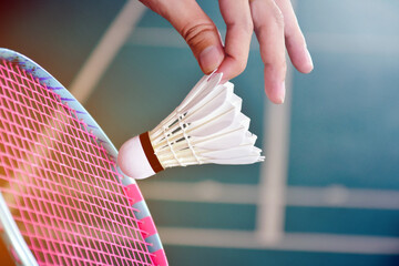Badminton serving by holding white shuttlecock feather in front of the racket with blur badminton...