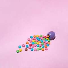 Easter violet egg with candies on pastel pink backgroung. Colorful creative concept.