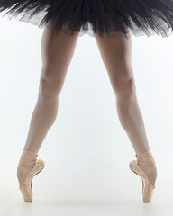 the legs of a ballerina standing on the tips of her fingers in close-up. photo shoots in the studio on a white background