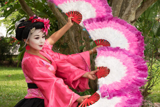 Latin woman wearing traditional geisha costume fancing with multiple fans