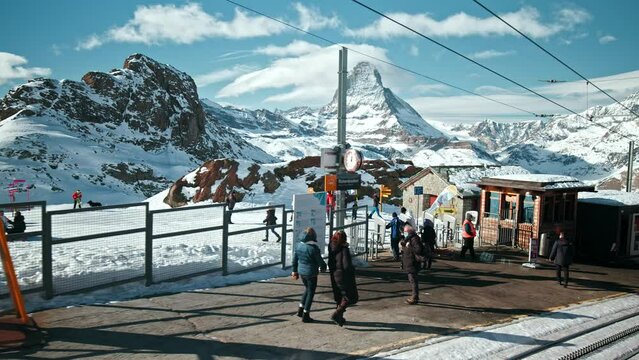 Ski resort in the Swiss Alps with the Matterhorn Mountain in the background. A crowd of People with ski equipment relaxing on a bright. sunny day in the mountains.