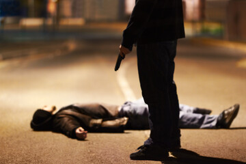 Acts of violence. Man lying on the ground after being shot by a gun-wielding criminal. - obrazy, fototapety, plakaty