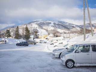 snow-covered cars in the parking lot and mountain range in nagano