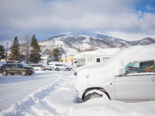 snow-covered cars in the parking lot and mountain range in nagano