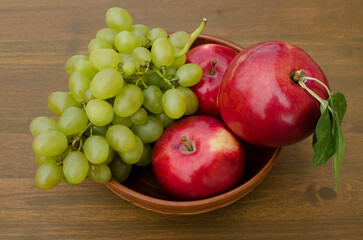 Fresh fruit: Red apples and grapes in a plate on the table close-up. Background still life.