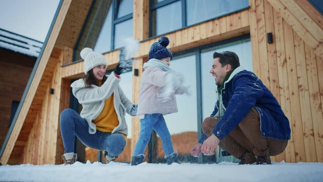 Happy young family on winter holiday in cabin with small child outdoors in snowy nature, snowfighting.