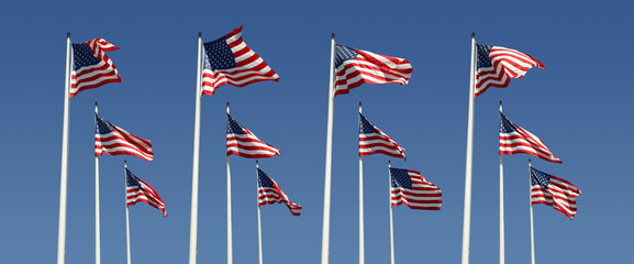 rows of american flags on a bright blue sky
