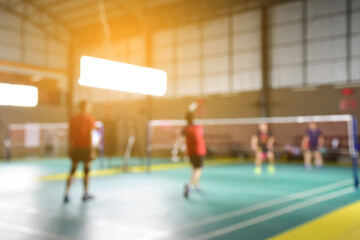 Blurred image of the badminton players and indoor badminton courts in modern gym.